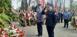 Komendant i strażak oddają honor pod pomnikiem