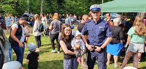 Policjant pozuje do zdjęcia z kobietą, która na rekach trzyma dziecko