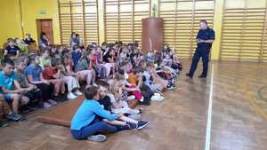 Policjant rozmawia z dziećmi, które siedzą na podłodze