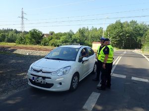 Mundurowi rozmawiają z kierowcą, który zatrzymał pojazd przed przejazdem kolejowym