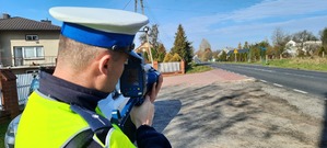 Policjant mierzy prędkość pojazdów poruszających się po drodze