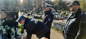 Policjant kładzie znicz na grób