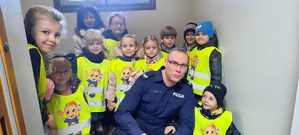 Policjant i dzieci w pomieszczeniu dla zatrzymanych