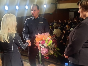 Policjant wręcza kwiaty kobiecie