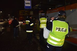 Policjanci i strażacy wręczaja odblaski przechodniom