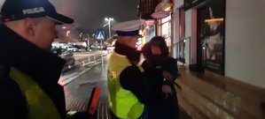 Policjanci wręczają kobiecie opaskę odblaskową
