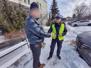 Na zdjęciu policjant rozdający odblaski