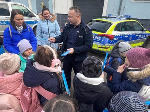 Na zdjęciu policjant rozdający odblaski dzieciom