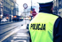 Na zdjęciu policjant ruchu drogowego stojący tyłem w kamizelce odblaskowej