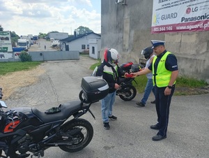 Na zdjęciu policjanci, którzy rozdają motocyklista odblaski i apteczki