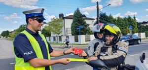 Na zdjęciu policjanci, którzy rozdają motocyklista odblaski i apteczki