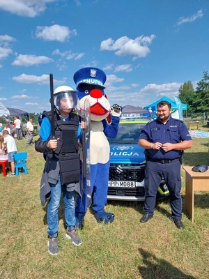 Na zdjęciu Sznupek, policjant oraz uczestnicy festynu robiące sobie zdjęcie