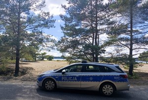 Na zdjęciu widać radiowóz policyjny na tle plaży