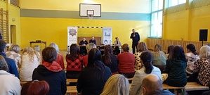 Na zdjęciu znajdują się uczestnicy spotkania oraz przemawiający naczelnik prewencji