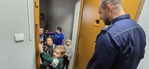 Na zdjęciu policjant oraz dzieci znajdujące się w pomieszczeniu dla osób zatrzymanych