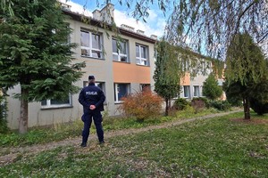Na zdjęciu policjant stojący przed szkoła