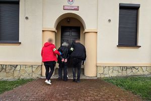 Na zdjęciu widać nieumundurowanych policjantów, którzy doprowadzają zatrzymanego