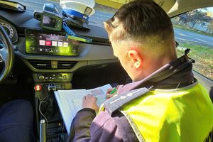 Na zdjęciu policjant wypisujący mandat karny