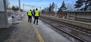 Na zdjęciu widać umundurowanych policjantów  w odblaskowych kamizelkach patrolujących dworzec PKP
