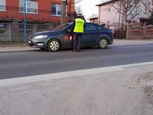 Na zdjęciu widać policjanta ruchu drogowego przeprowadzającego badanie trzeźwości