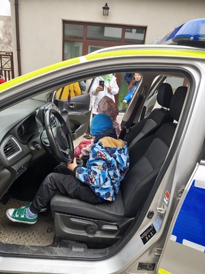 Zdjęcie przedstawia dziecko siedzące w radiowozie