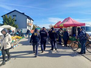 Na zdjęciu widać strażników miejskich oraz dzielnicowego, którzy znajdują się na targowisku miejskim