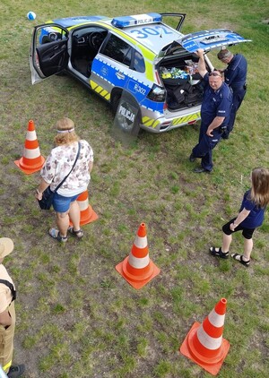Zdjęcie policjantów i uczestników festynu przy radiowozie.